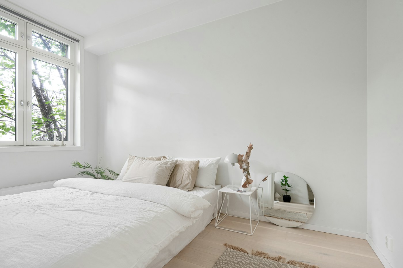 A white bedroom with a bed, window, and clear floor beside the bed.