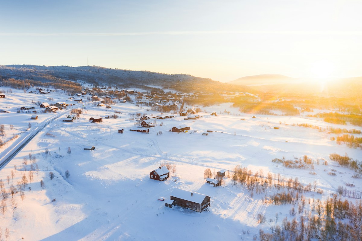 A snowy landscape with a real house in the distance.