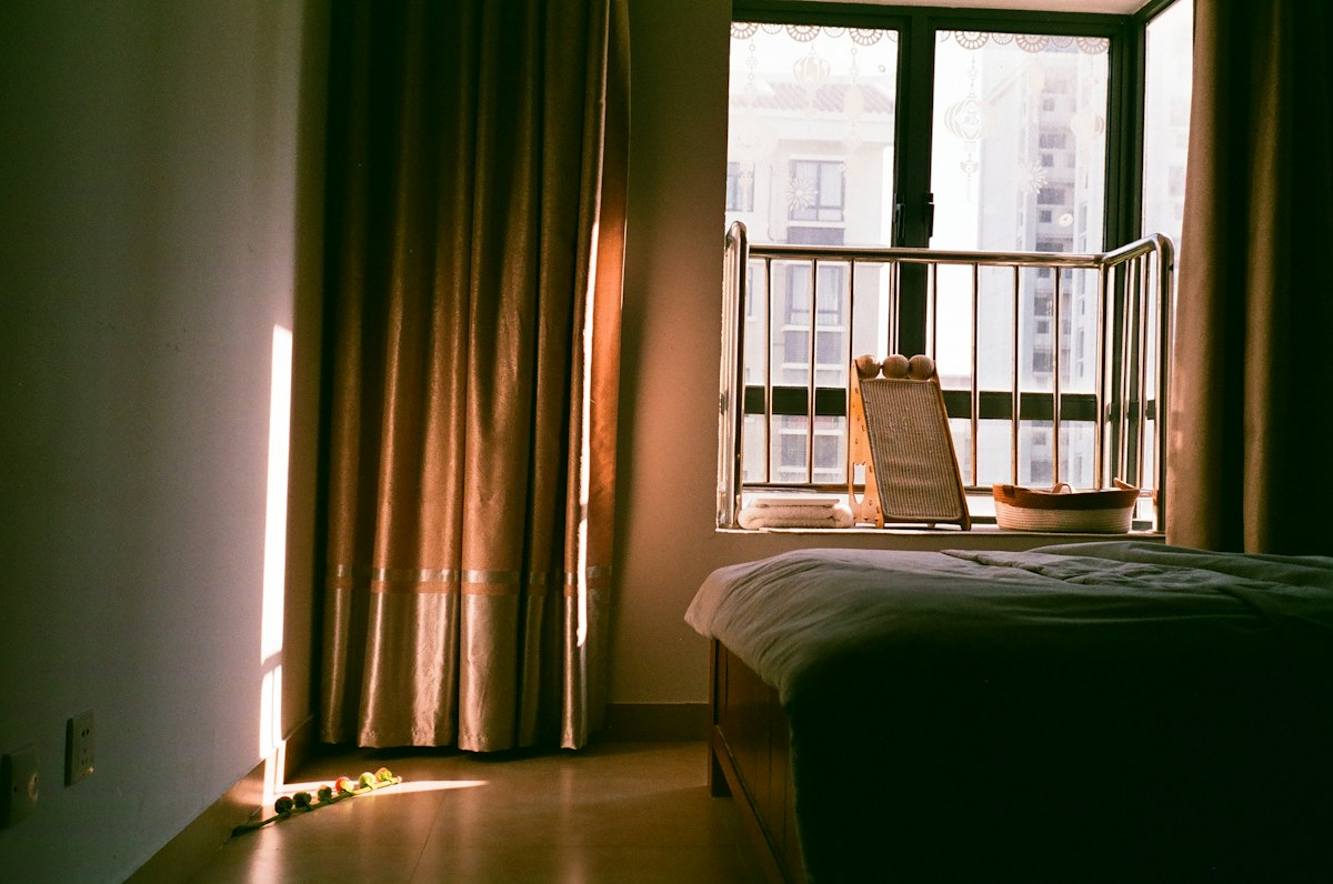 A real bedroom with sunlight passing through window curtains.