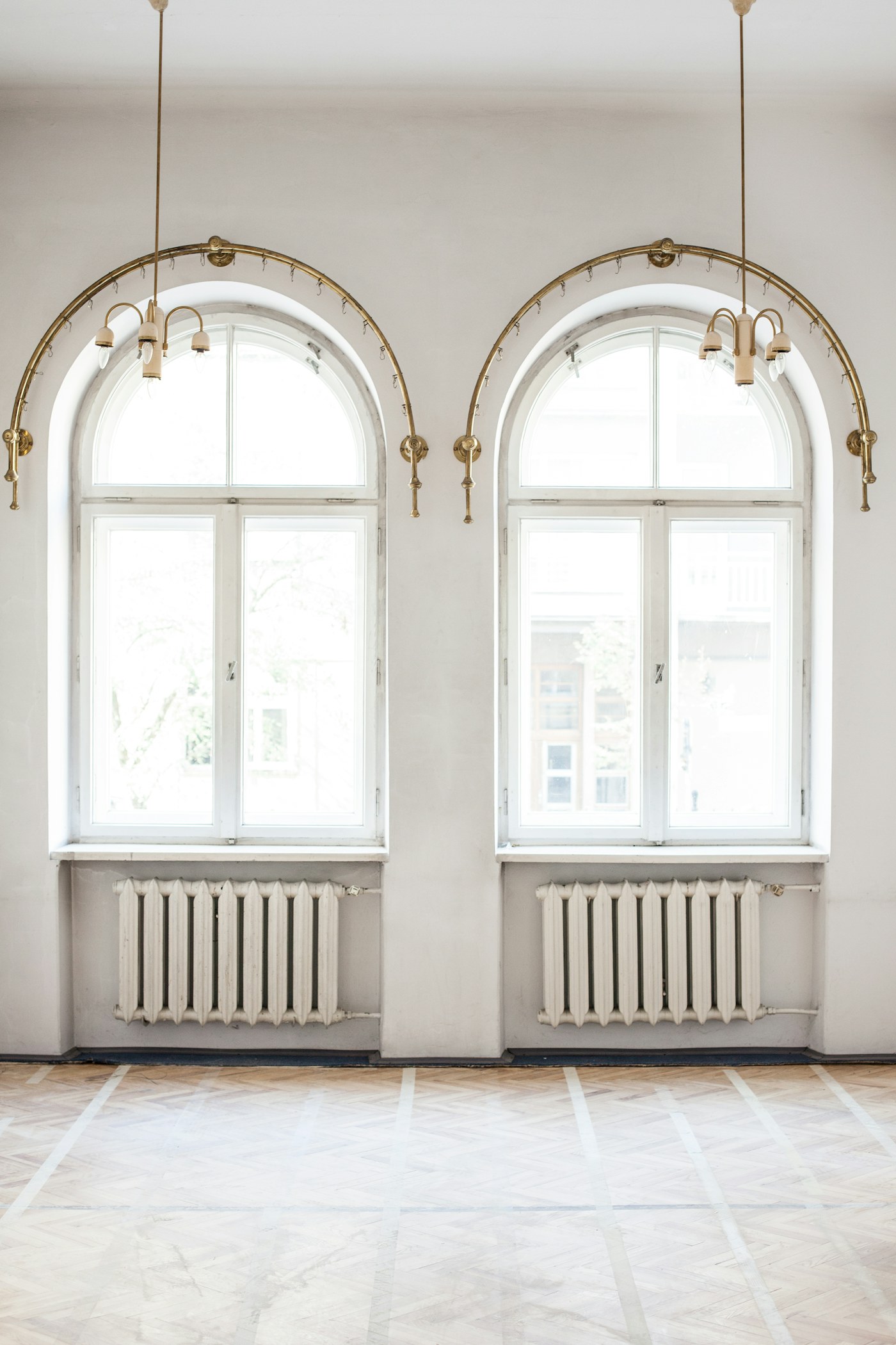Interior wall with two arched windows, painted frames and radiators beneath